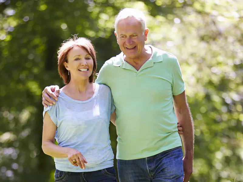 A husband and wife walk arm in arm in the park