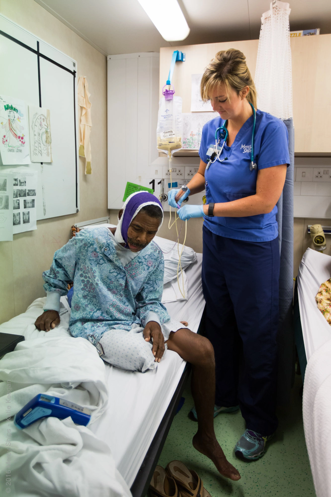 ©2016 Mercy Ships - Crédito de la foto Katie Keegan - La enfermera de la sala Nikki VERMEER (EE. UU.) atiende a un paciente en la sala maxilofacial.